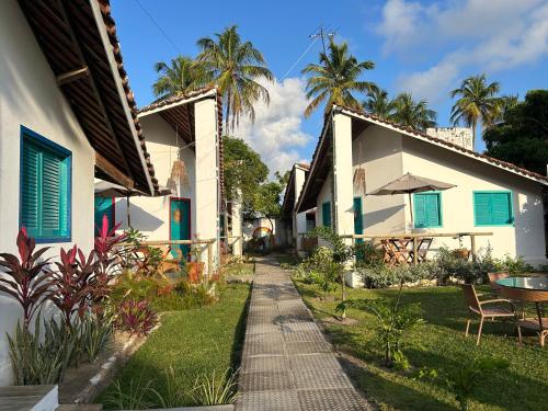 タマンダレーにあるCAJUEIROS - Chales Aconchegantes a 2 Minutos da Praiaの椰子の木が立ち並ぶ二棟の間の通路