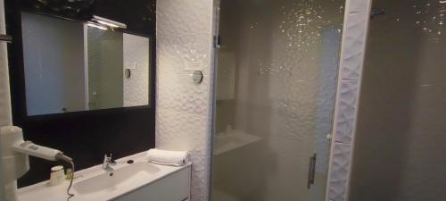a bathroom with a sink and a shower with a mirror at Logis Grand Hotel Pelisson in Nontron