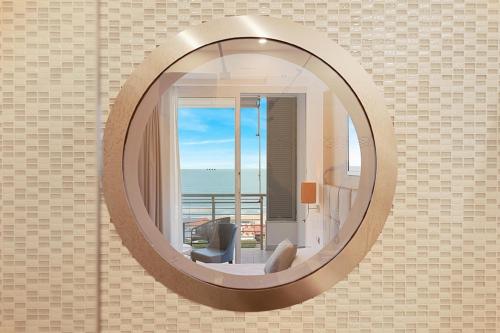 a round mirror on a wall with a view of the ocean at Hotel Excelsior in Marina di Massa