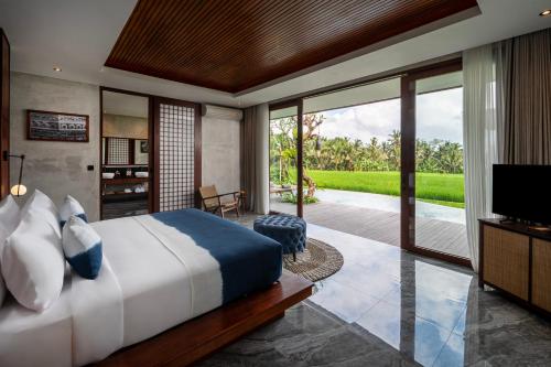 a bedroom with a bed and a television and a patio at Inara Alas Harum in Ubud