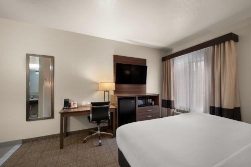 a hotel room with a bed and a desk and a television at Comfort Inn & Suites in Fenton