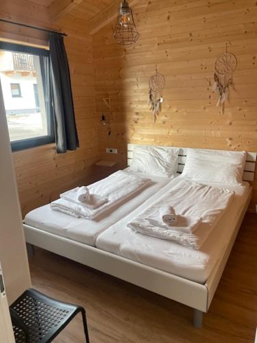 a bed in a room with a wooden wall at Bungalow Rattendorf - bij skigebied Nassfeld in Hermagor
