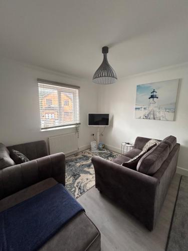 a living room with two couches and a tv at The Loft and The Den Apartments in Sandown