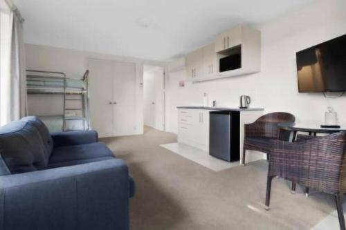 Una sala de estar con un sofá azul y una cocina. en Bushview Retreat, en Paihia