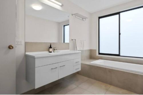 baño con lavabo blanco, bañera y ventana en Bushview Retreat, en Paihia