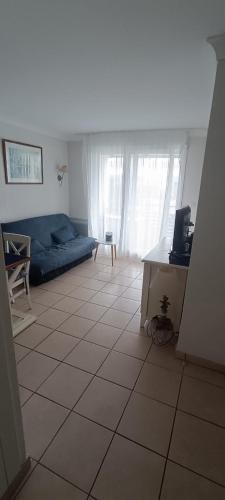 - un salon avec un canapé bleu et du carrelage dans l'établissement Appartement T2 lacanau ocean, à Lacanau-Océan