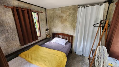 a small bedroom with a bed and a window at Seven 50s in Pai