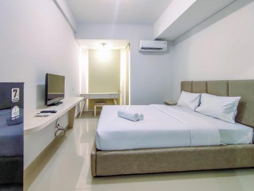 a bedroom with a bed and a desk with a television at Elegant and Comfy Studio Barsa City Apartment By Travelio in Seturan
