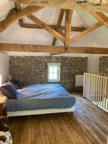une chambre avec un lit dans un mur de pierre dans l'établissement Vakantiehuis La Poire, op landgoed aan de Dordogne, à Prudhomat