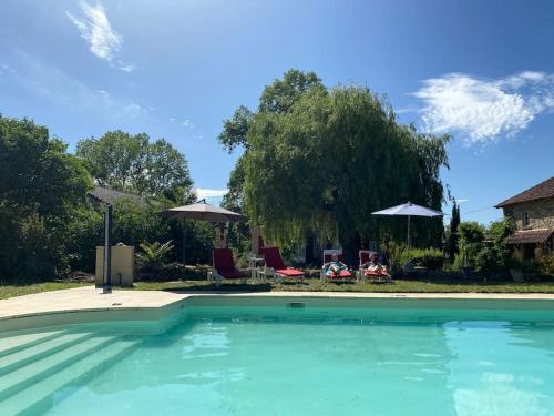 a swimming pool with chairs and umbrellas at Vakantiehuis La Poire, op landgoed aan de Dordogne in Prudhomat