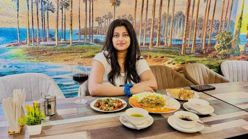 a woman sitting at a table with a plate of food at Raksha Suites & Banquet Greater Noida in Greater Noida