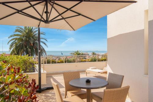 a patio with a table and chairs and an umbrella at Hotel Excelsior in Marina di Massa