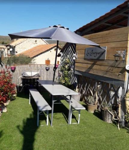 - une table et des chaises sous un parasol dans la cour dans l'établissement Havre de paix dans les Gorges du Tarn, à Rivière-sur-Tarn