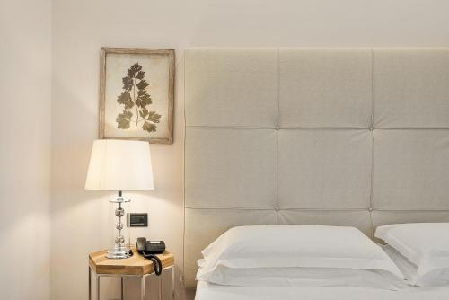 a bed with a headboard and a lamp on a table at Hotel Excelsior in Marina di Massa