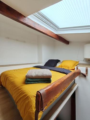 - une chambre avec un lit jaune et une lucarne dans l'établissement La Cabane Parisienne - Au centre de Paris - Lumineux - Vue panoramique, à Paris