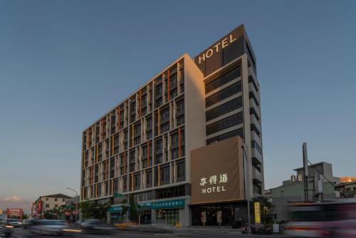 ein Hotelgebäude an einer belebten Stadtstraße mit Autos in der Unterkunft In Joy Hotel in Taichung