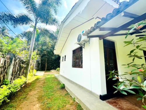 a white house with a window and a door at Peak House in Hiriketiya