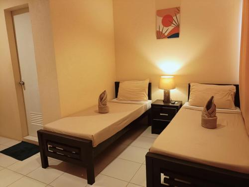 two beds in a room with a lamp on a table at Claytown Pension House in Dumaguete