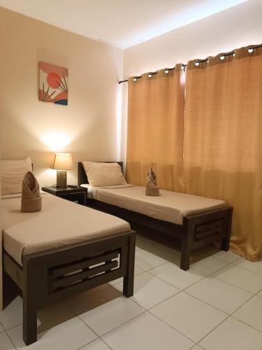 a room with two beds and a lamp and curtains at Claytown Pension House in Dumaguete