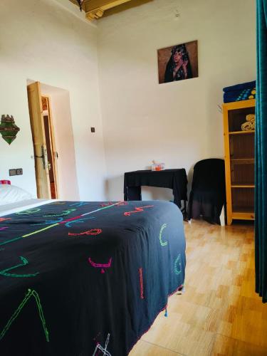 a bedroom with a bed with a blue blanket at Le Retour au calme Maison d'hôtes in Tinerhir