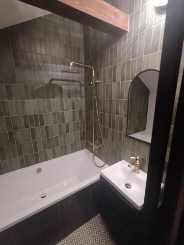 a bathroom with a tub and a sink and a mirror at Dwór pod Sosnami Kaszuby, sauna in Ostrzyce