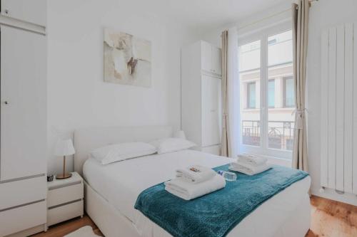 une chambre blanche avec un lit avec des serviettes dessus dans l'établissement Charming Apt - 1BD-4P - Tour Eiffel - Invalides, à Paris