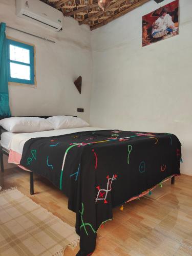 a bed in a room with a black blanket on it at Le Retour au calme Maison d'hôtes in Tinerhir