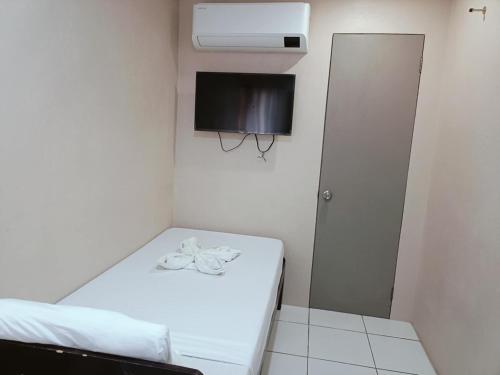 a small room with a bed and a tv at Claytown Pension House in Dumaguete