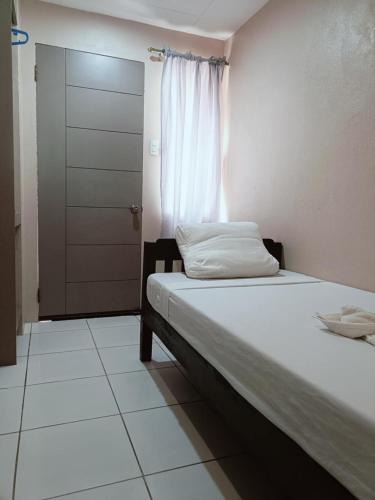 a bedroom with a bed with a window and a door at Claytown Pension House in Dumaguete