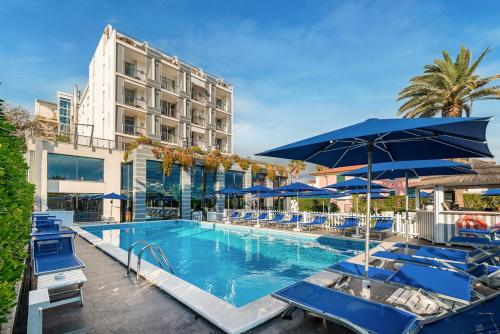 a pool with chairs and umbrellas next to a building at Hotel Excelsior in Marina di Massa