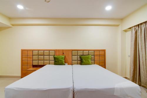 a bedroom with a large white bed with green pillows at HOTEL Urban Asia in kolkata