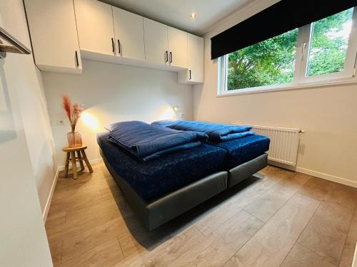 a bed in a room with a large window at Bungalowpark de Horn - Floresta 214 in Dirkshorn