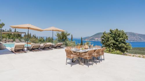 a dining room with a table and chairs and the ocean at Fiscardo Sunny Villas in Fiskardho