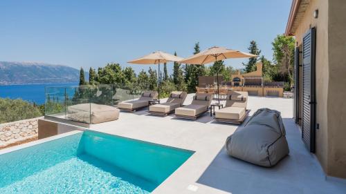 a pool with chaise lounge chairs and an umbrella at Fiscardo Sunny Villas in Fiskardho