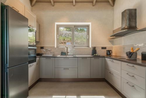a kitchen with white cabinets and a window at Fiscardo Sunny Villas in Fiskardho