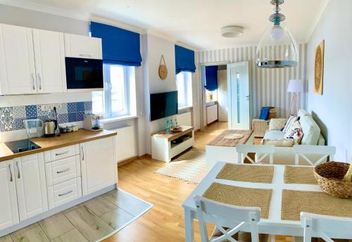 kuchnia i salon z białymi szafkami i stołem w obiekcie Apartament Łazienna River View AC Progres w Toruniu