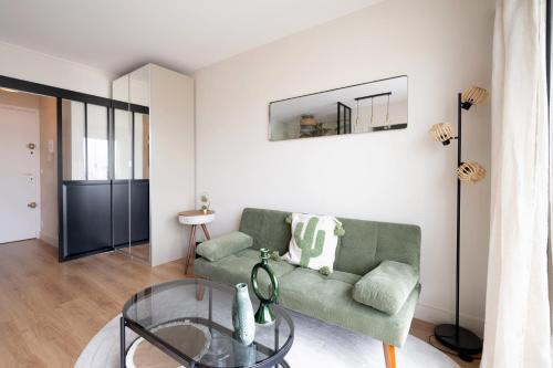 - un salon avec un canapé vert et une table en verre dans l'établissement Studio avec balcon - Paris 17e, à Paris