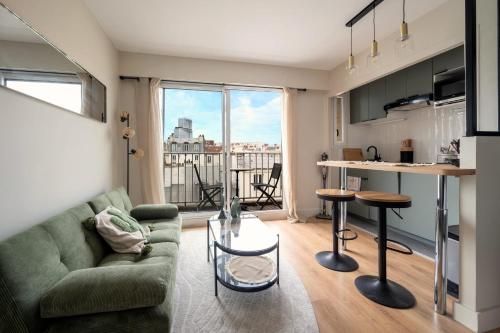 un salon avec un canapé vert et une cuisine dans l'établissement Studio avec balcon - Paris 17e, à Paris