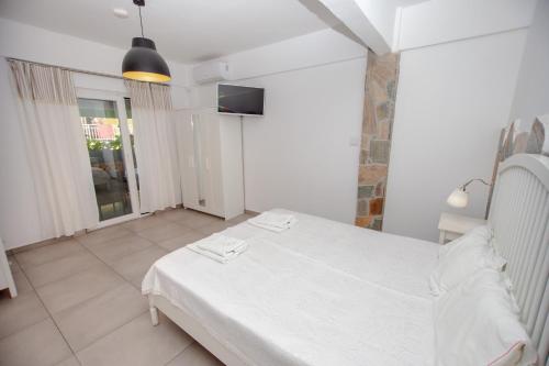 a bedroom with a white bed and a television at T H E BERLIN Studios and Suites in Nea Vrasna