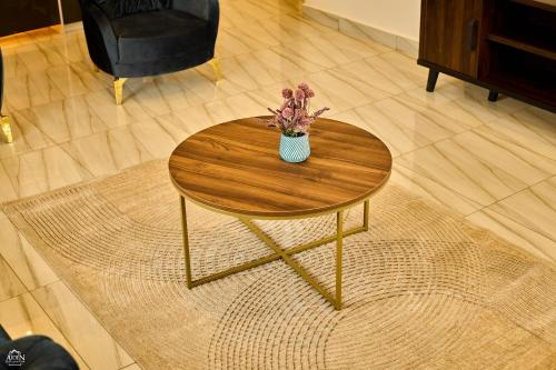 a wooden table with a vase of flowers on it at AIDEN HOMES AND APARTMENTS HOTEl in Koforidua