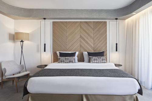 a bedroom with a large bed and a chair at Atlantica Caldera Palace in Hersonissos