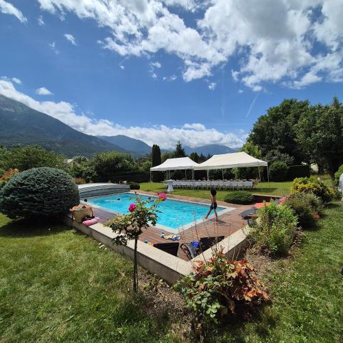 une personne se tient à côté d'une piscine dans l'établissement Chambres d'hôtes Les Peschiers, à Châteauroux-les-Alpes