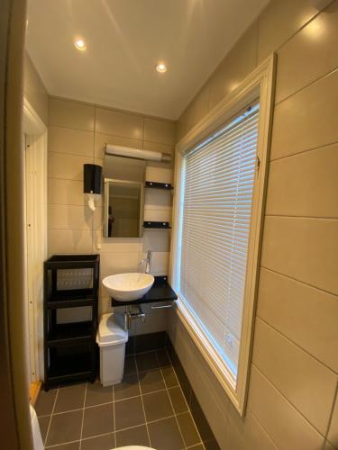 een badkamer met een wastafel en een toilet en een raam bij Sjarmerende leilighet i hjertet av Risør in Risør