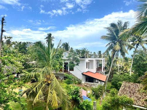 a house in the middle of a forest with palm trees at Peak House in Hiriketiya