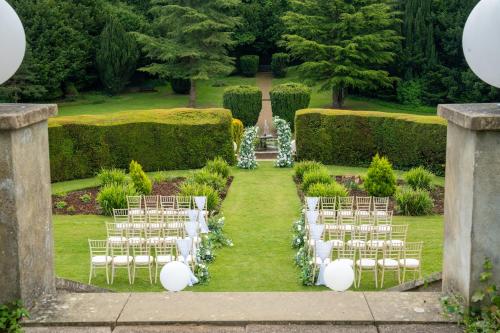 a row of white chairs in a garden at Hunton Park Hotel in Kings Langley