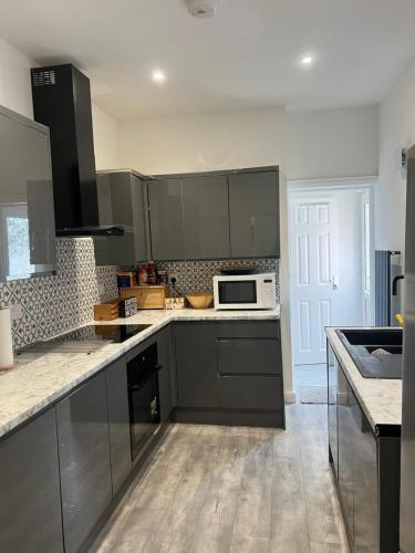 una cucina con armadi grigi e forno a microonde bianco di Southampton Bridge Home by AFL a Northampton