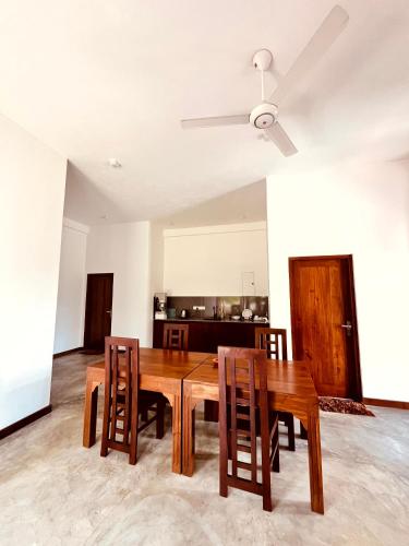 a dining room table with chairs and a ceiling fan at Peak House in Hiriketiya