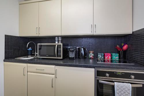 a kitchen with white cabinets and a microwave at Cary Arms & Spa in Torquay