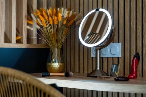 a desk with a mirror and a vase of flowers at L'Amour d'Or Centre Historique in Besançon
