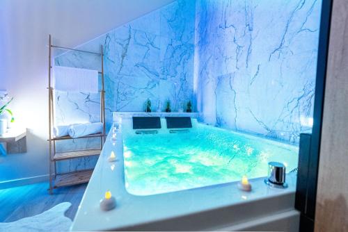 a blue bathroom with a tub with water in it at L'Amour d'Or Centre Historique in Besançon